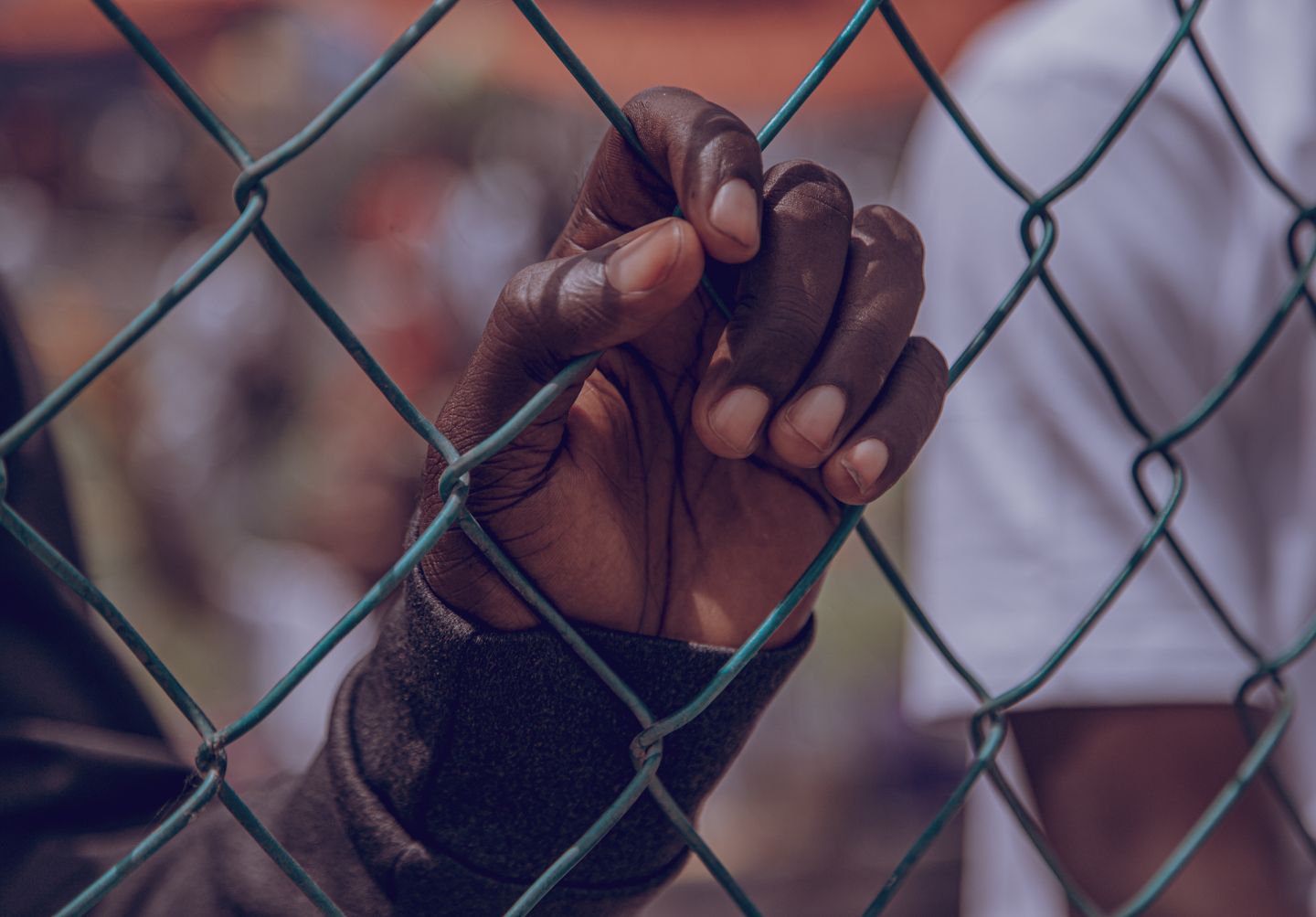 Woman's hand holding a chain link fence