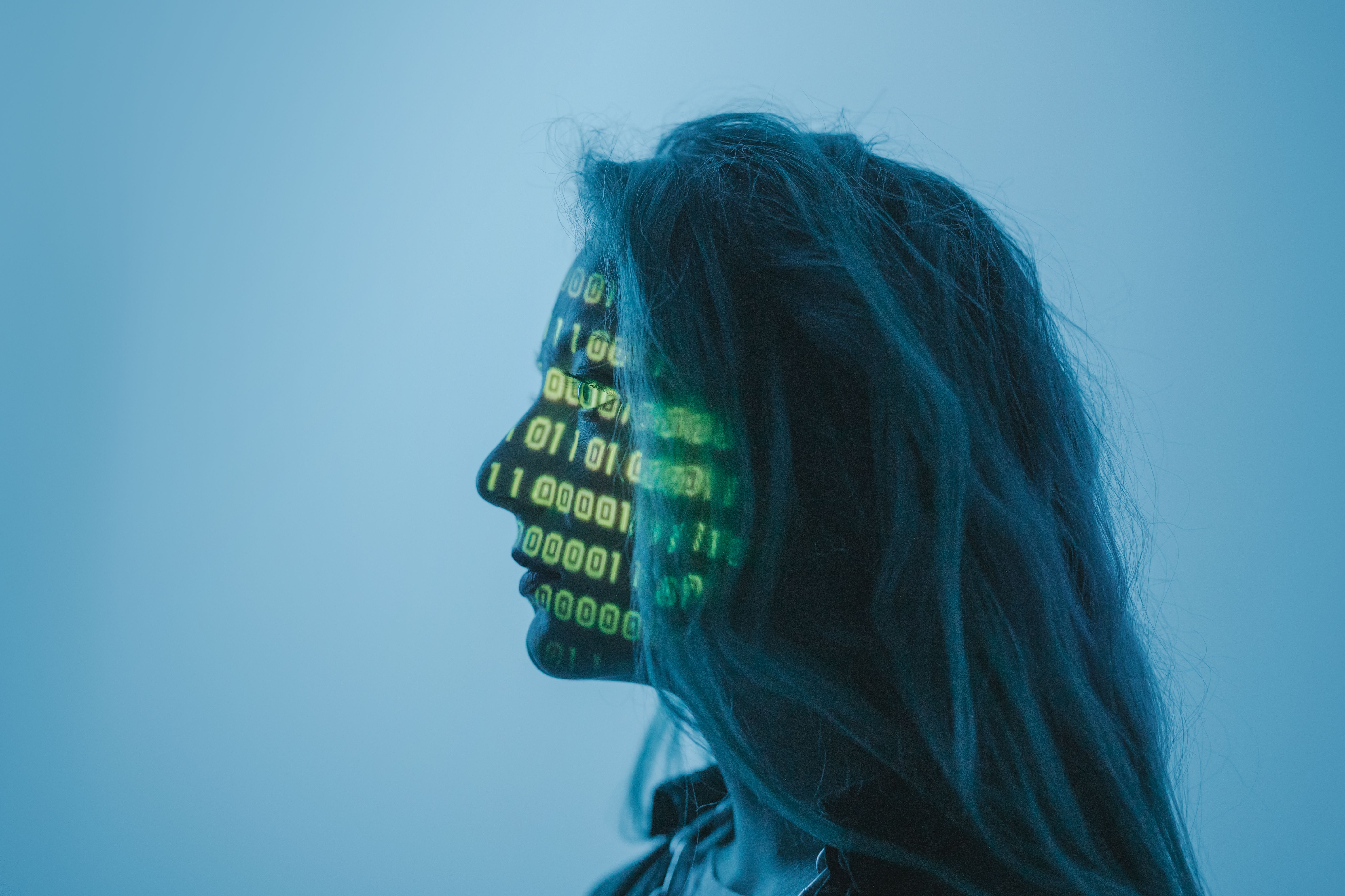 A woman in profile with binary code projected onto her face.
