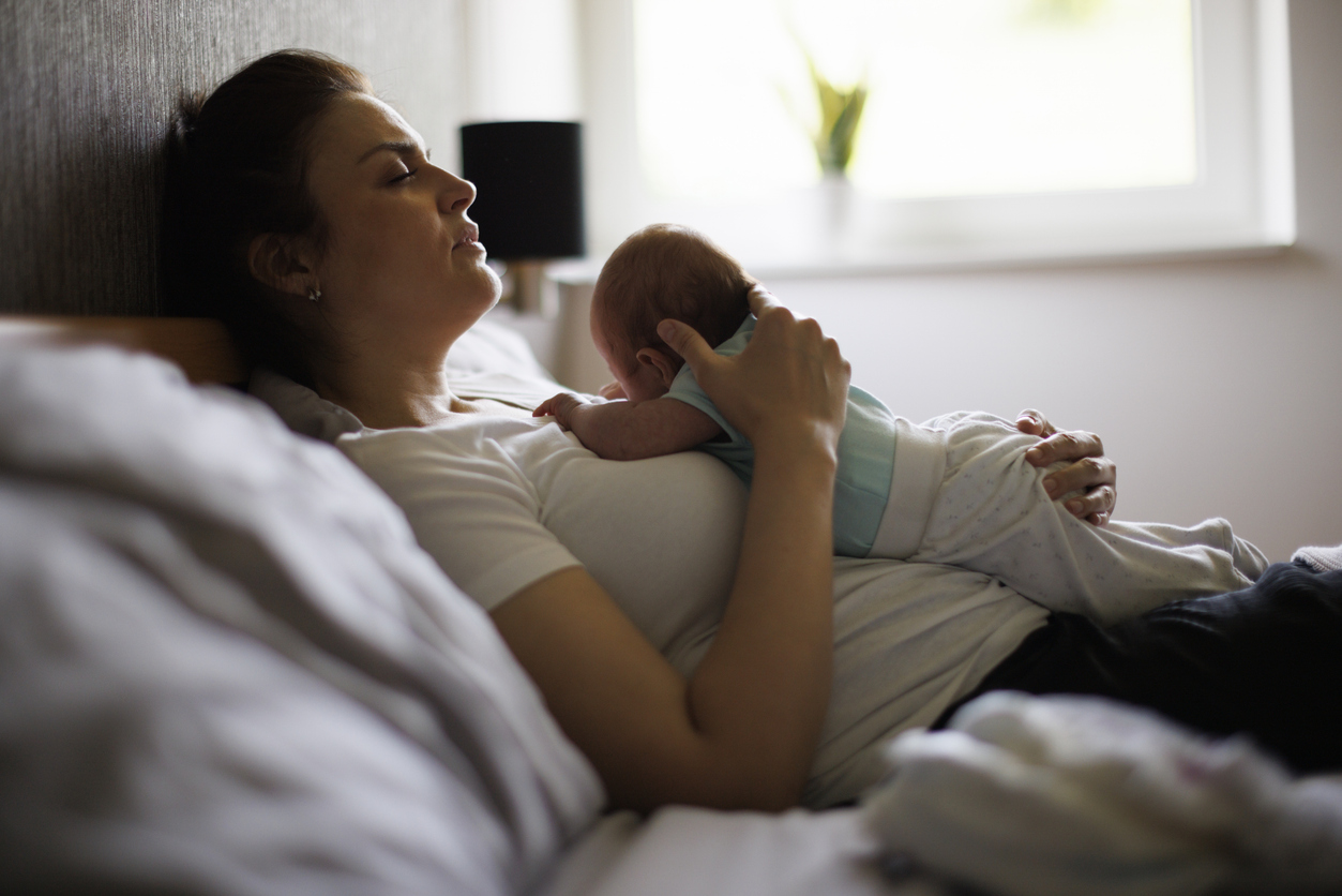 A woman cradling her baby post pregnancy