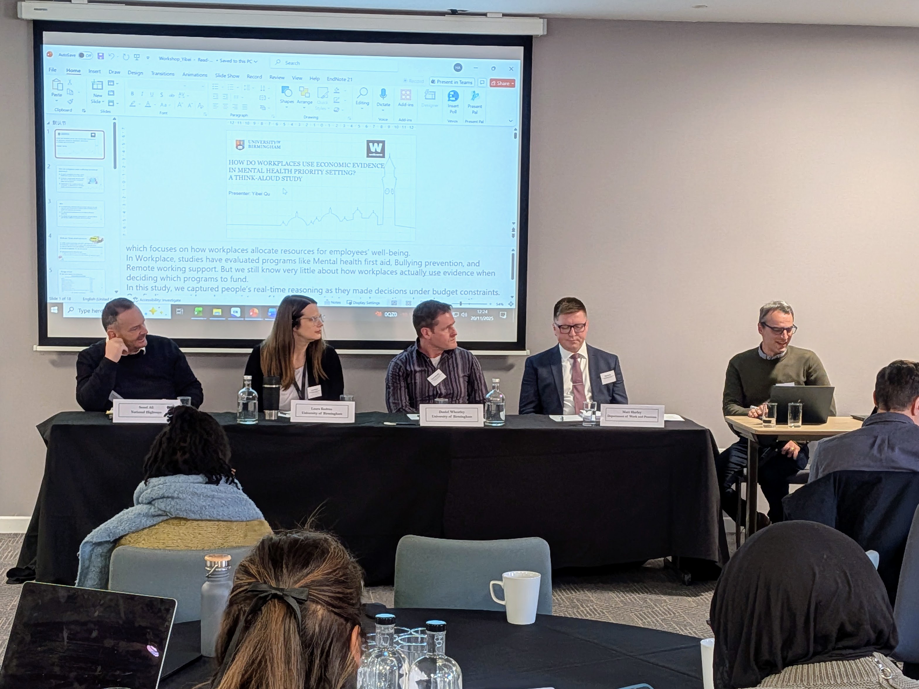 A panel discussion with five people sat at a table in front of an audience.