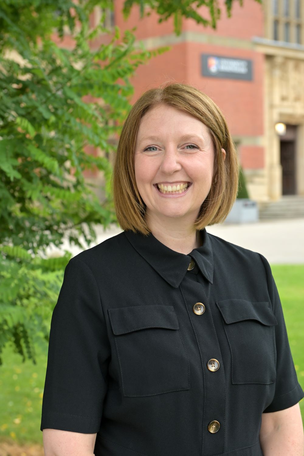 Zoe Hurley stands in front of the Aston Webb building, with greenery in the background