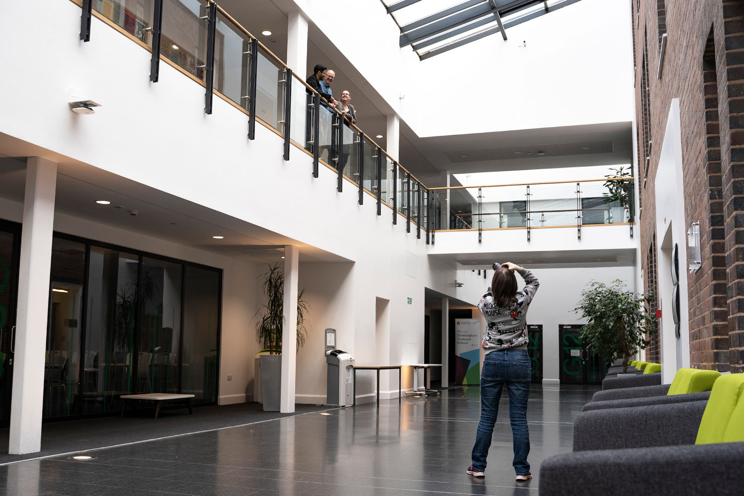 A woman taking a photo of people stood on a balcony