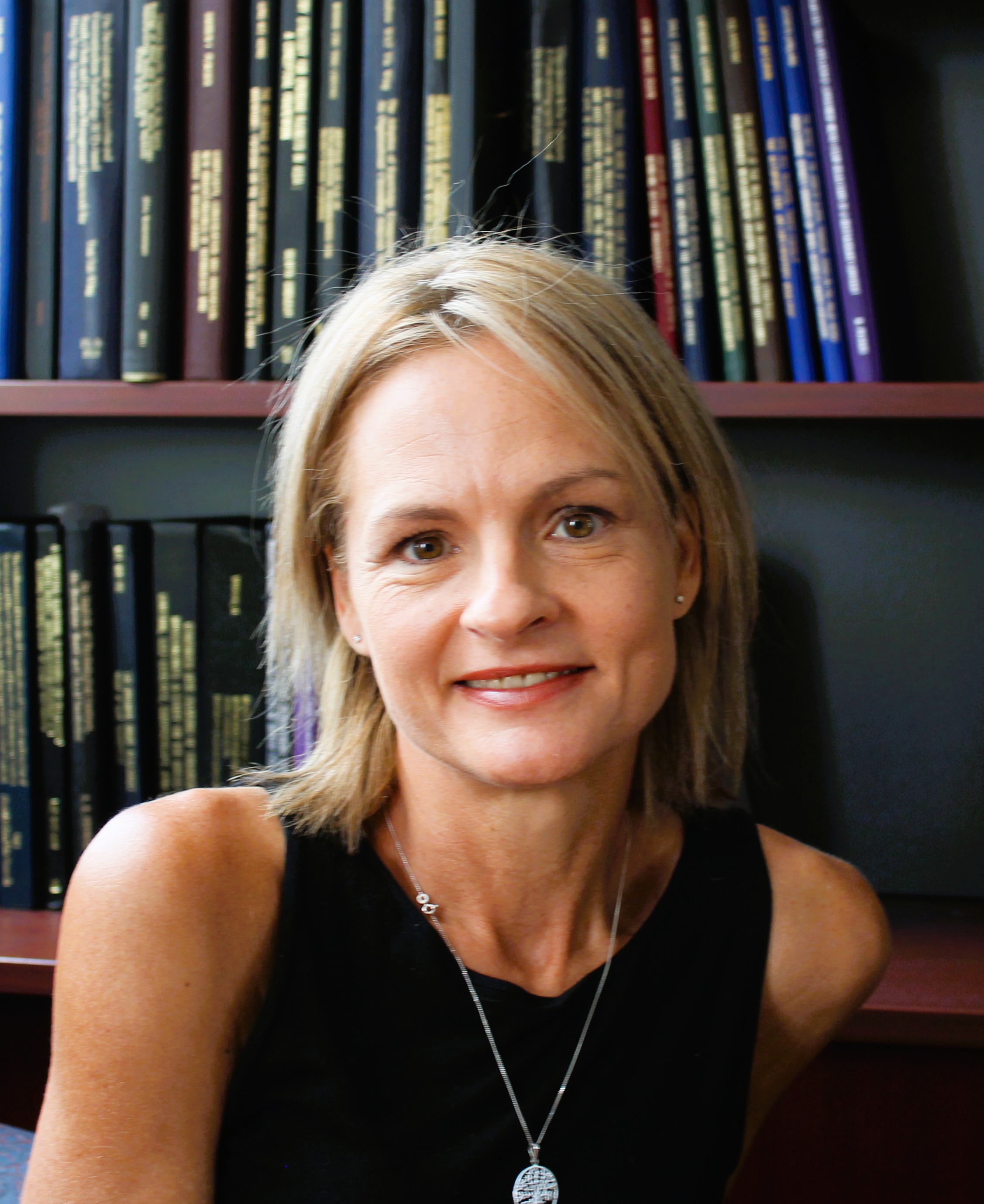 Dr Christa Viljoen sitting in from of a bookcase