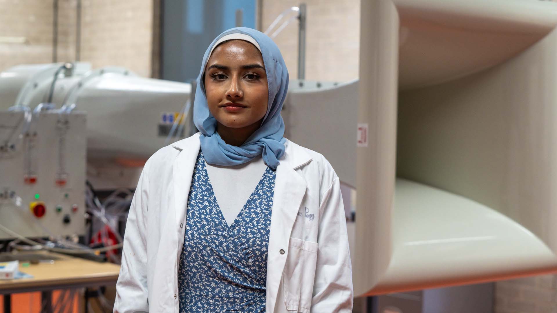Student Sumaya standing in front of equipment in the aerospace engineering ab