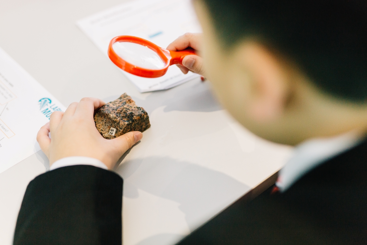 A student examines a rock specimen with a magnifying glass.