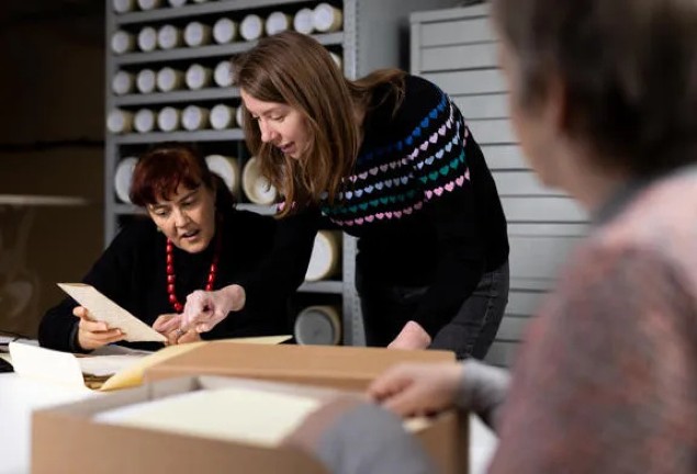Two women discussing a leaflet taken from a box