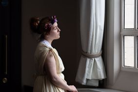 Person in period costume looking out of a window