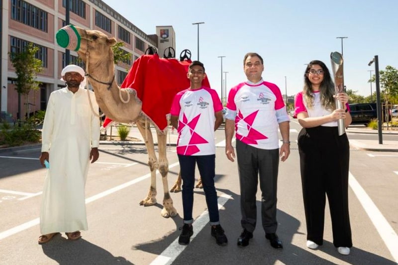 Lord Bilimoria standing with student Batonbearers at the University of Birmingham 's Dubai campus.