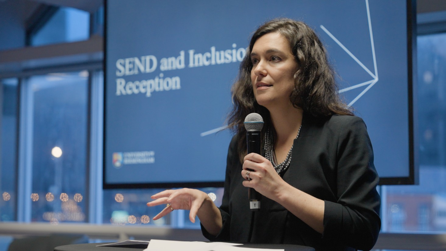 Professor Susana Castro-Kemp holding a microphone delivering a speech at Labour Party Conference event