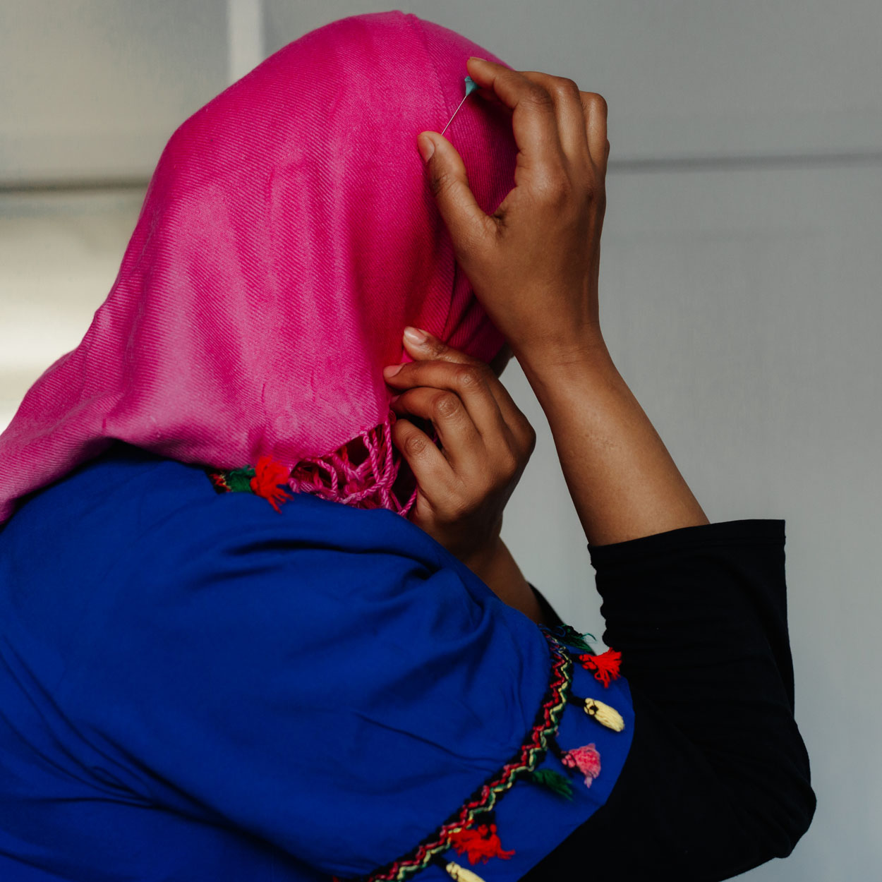A woman with a pink head scarf looks away from camera