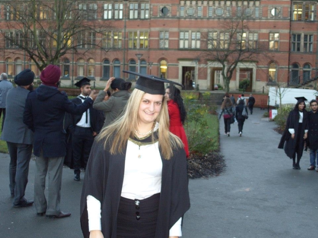 Megan in her graduation cap and gown at graduation, with the Law building in the background.
