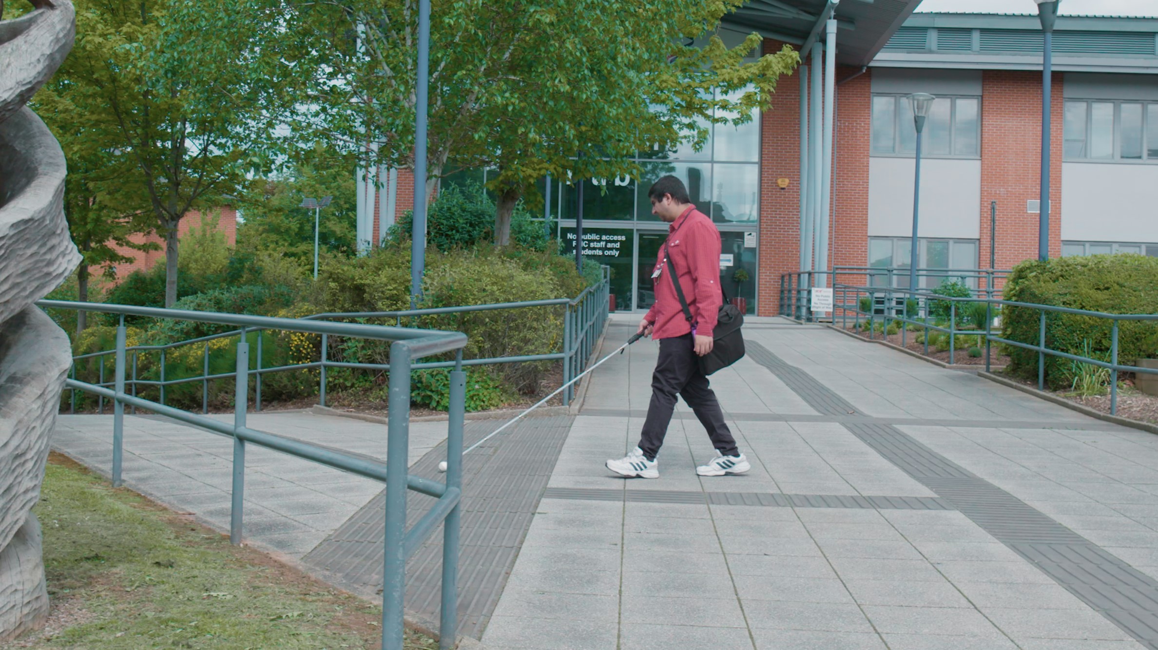 Young person with vision impairment walking using a cane