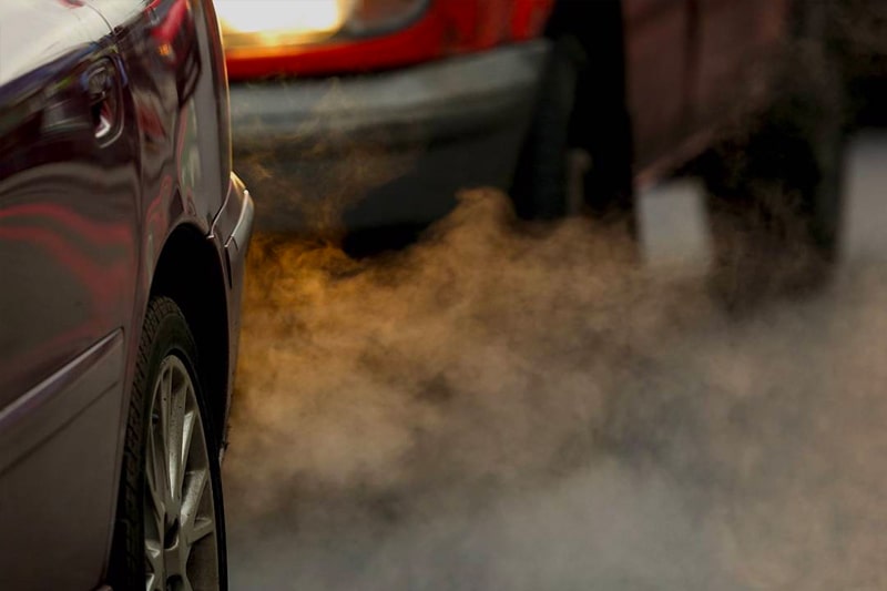 Stationary vehicles in a queue of traffic with their exhausts emitting fumes