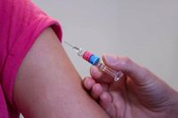 A persons arm being injected with Pfizer's COVID-19 vaccine