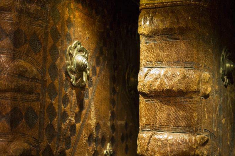 Two old leather-bound, patterned books with one featuring a circular metal boss