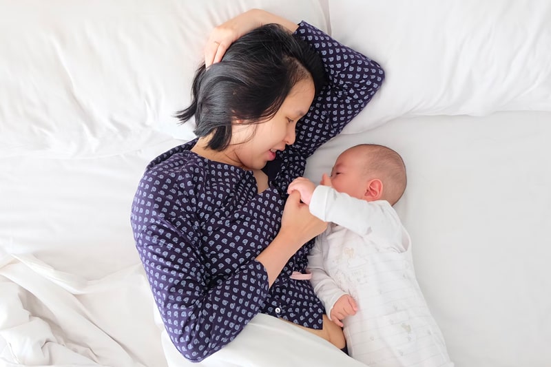 Mother and baby lying on a bed together