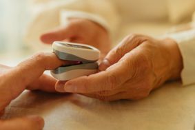 Person attaching a pulse oximeter to an old person's finger