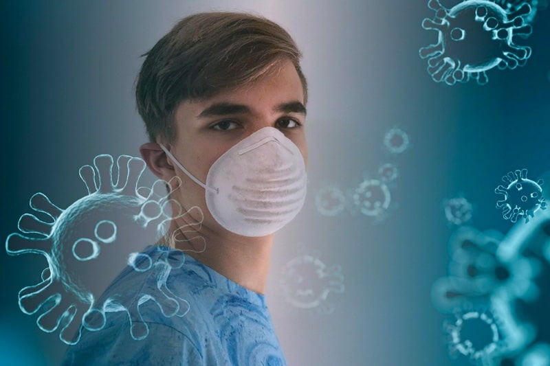 Teenage boy wearing a face mask with overlaid coronavirus cells