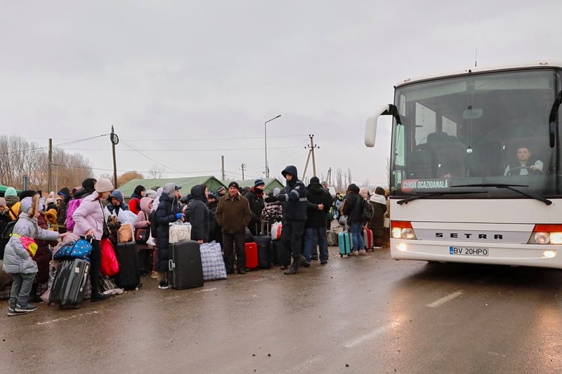 Ukrainian refugees queuing to get on a coach with their belongings