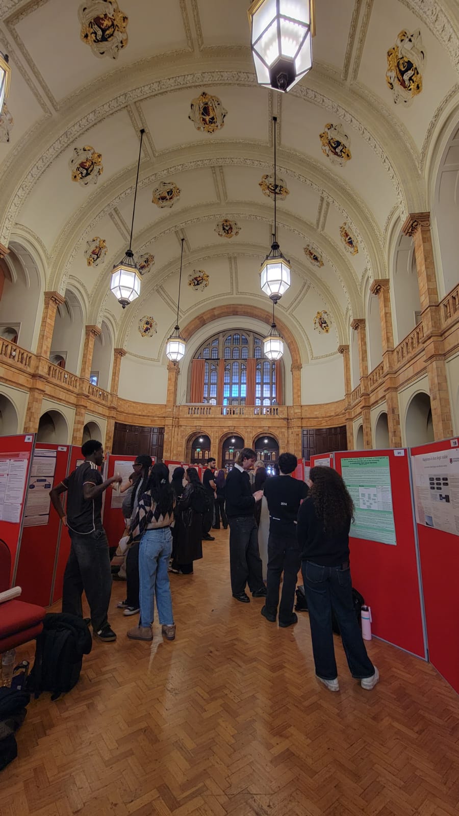 People stood looking at posters hung up on boards in a grand hall.