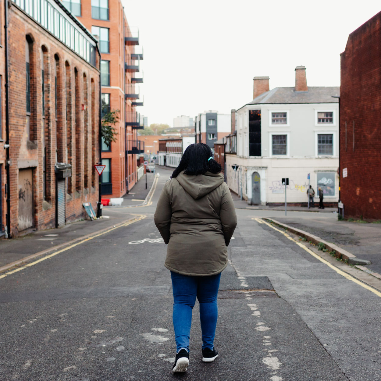 A woman in a green coat with her back to the camera