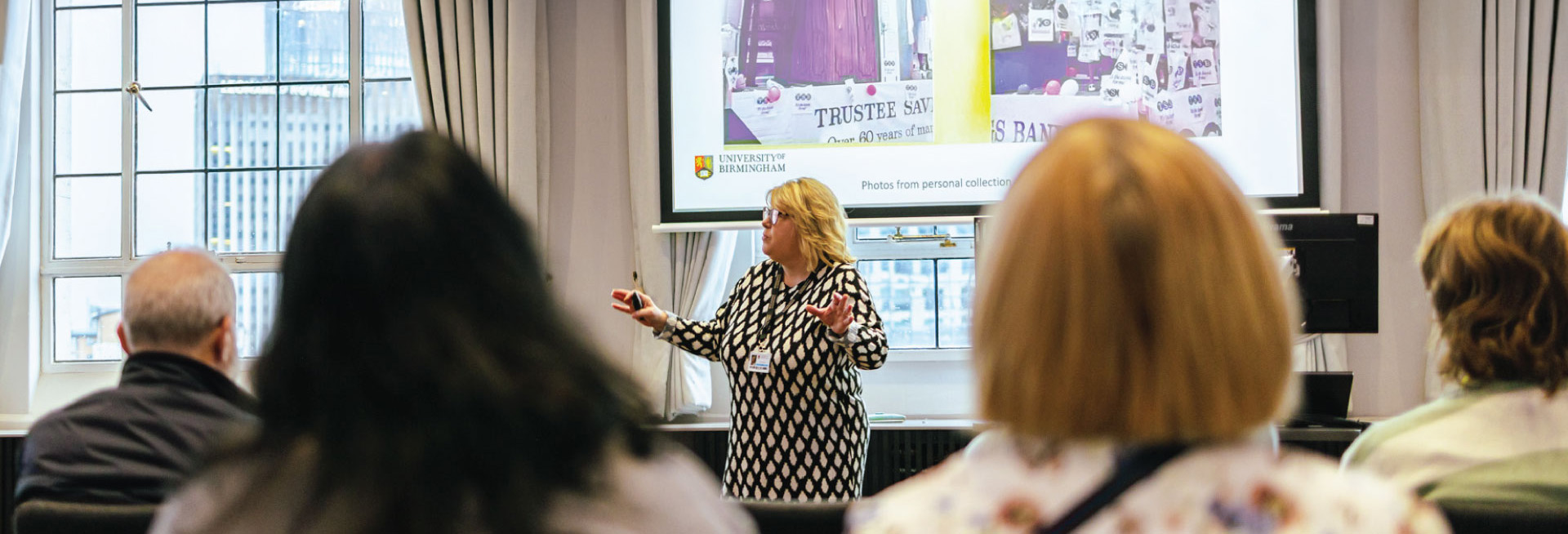 A woman with blonde hair delivers a talk to a seated audience.