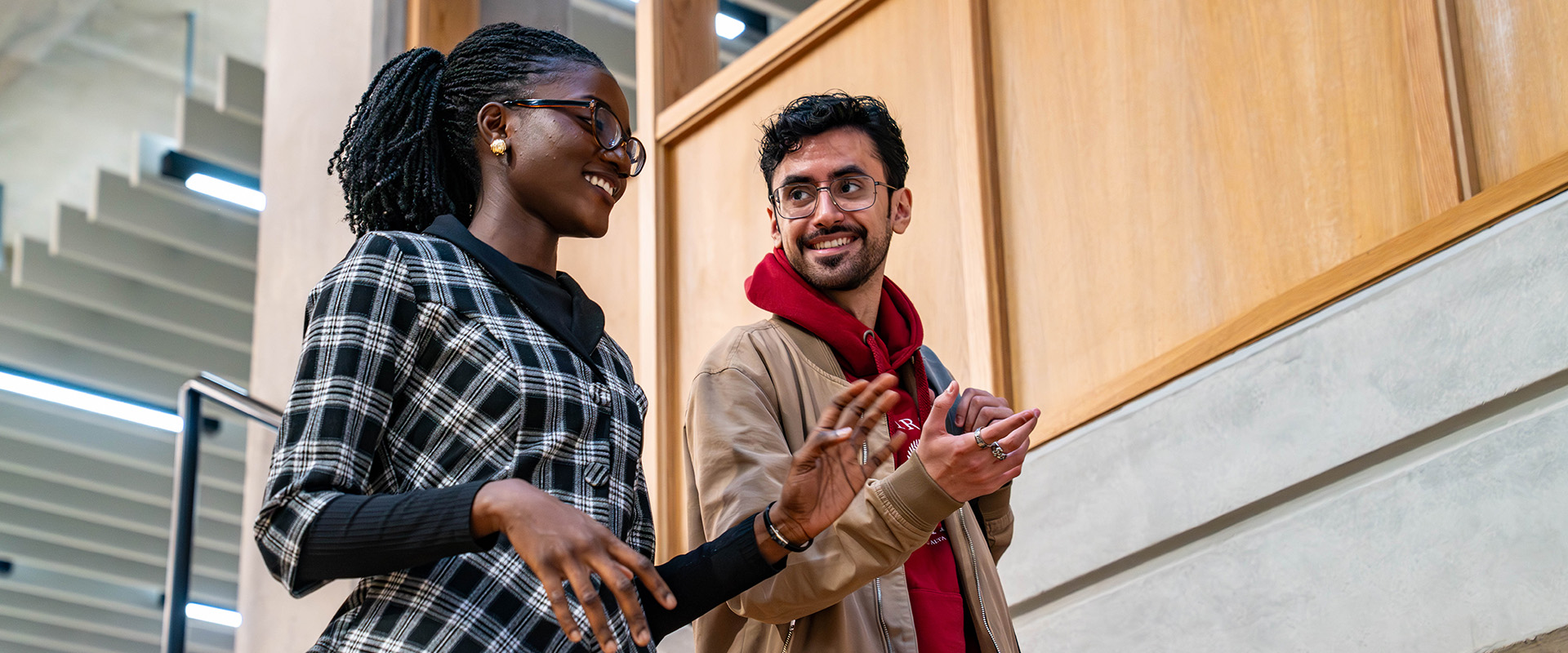 Two students walking and talking down the stairs