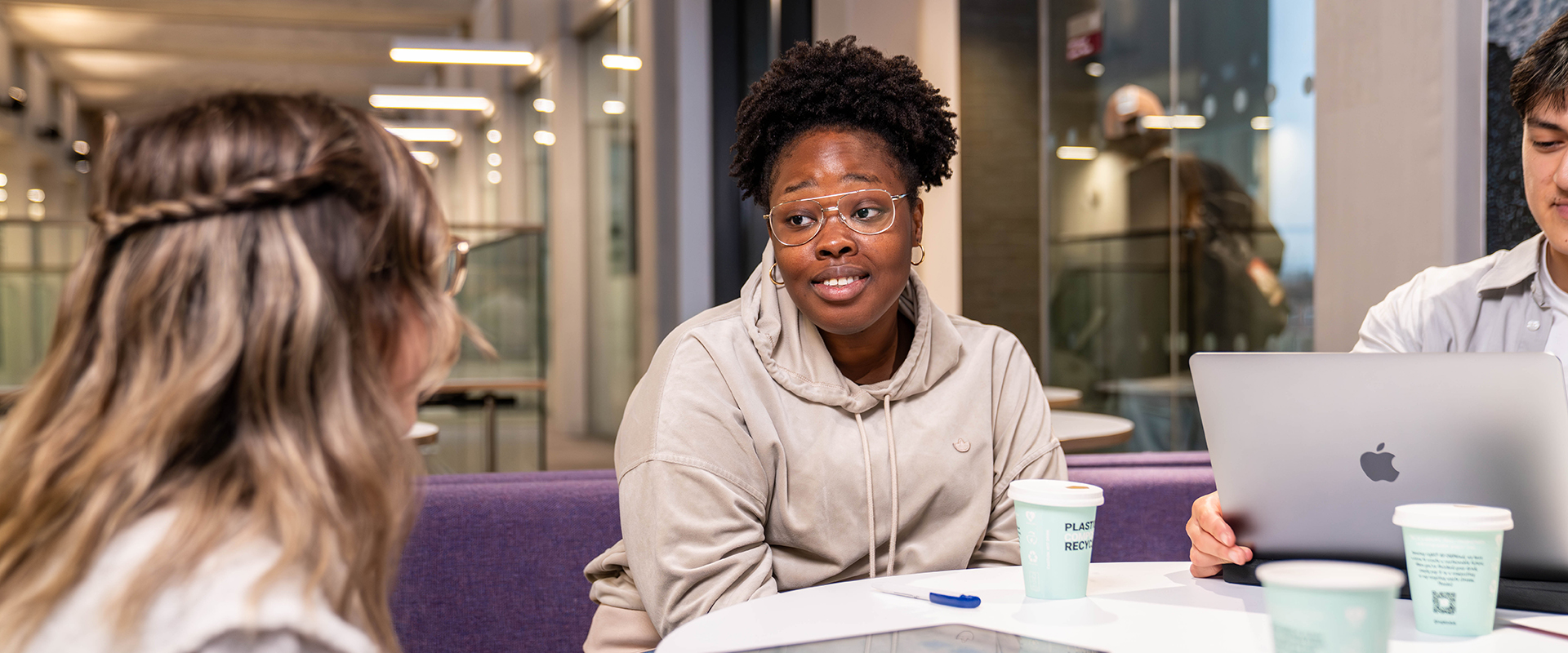 Group of students sat at a table with laptop and coffee cups