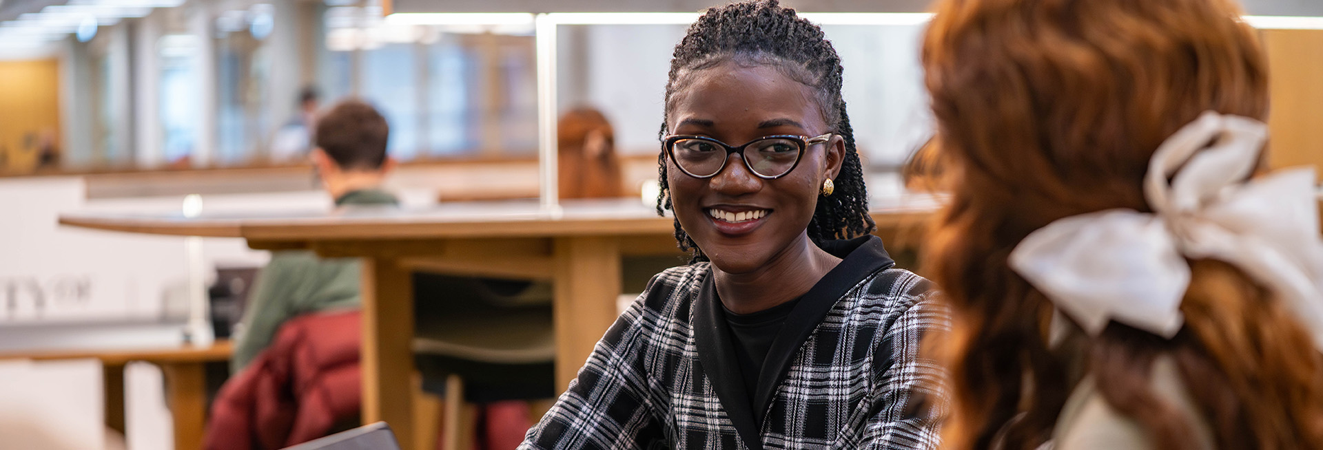 Two female students sat talking at a table