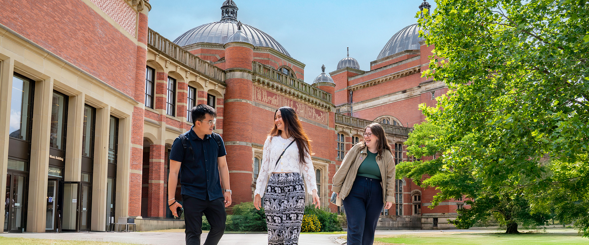 Three students walking in front of Aston Webb Building