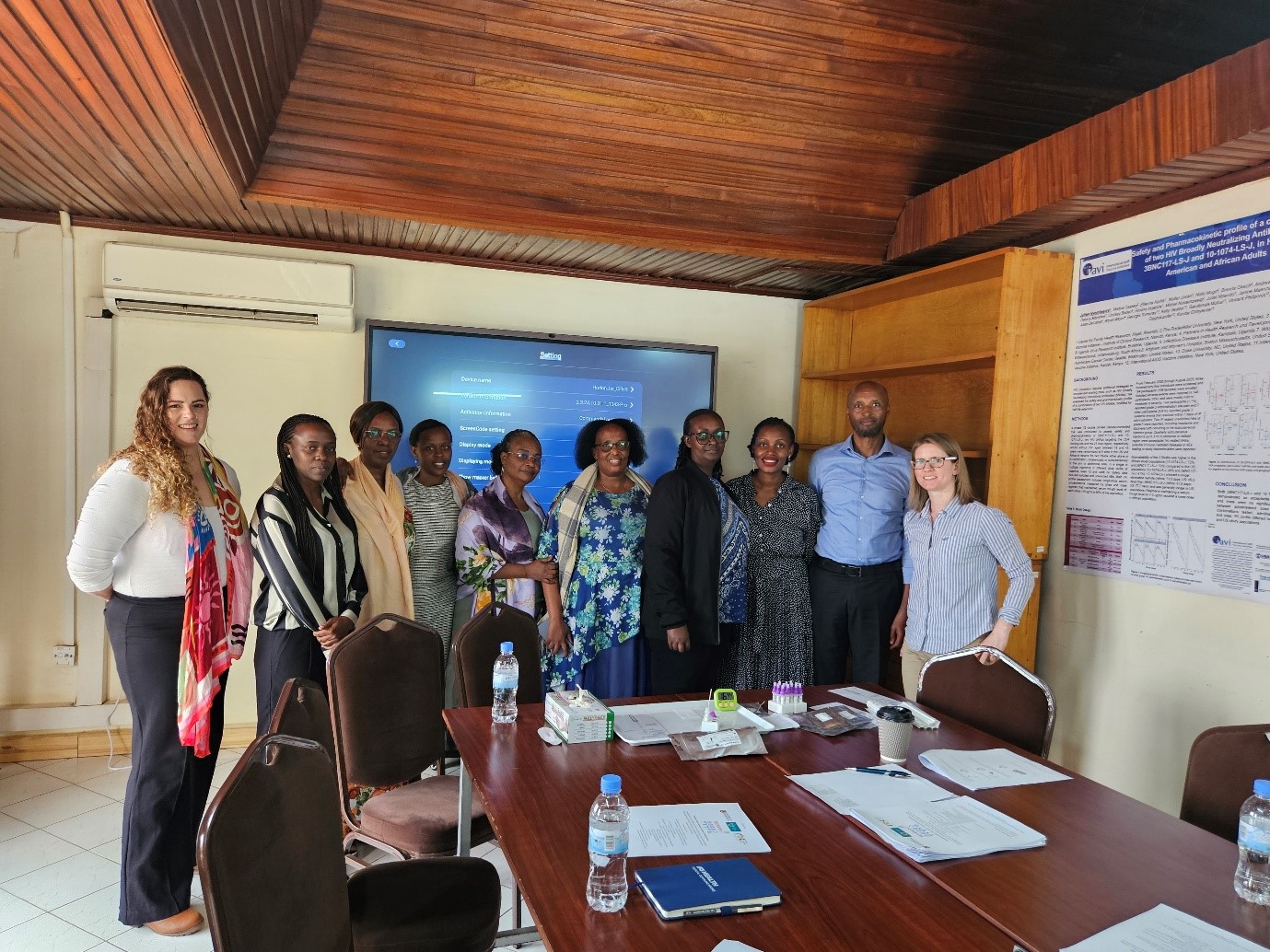 Group photo in meeting room, stood in front of screen for presenting.