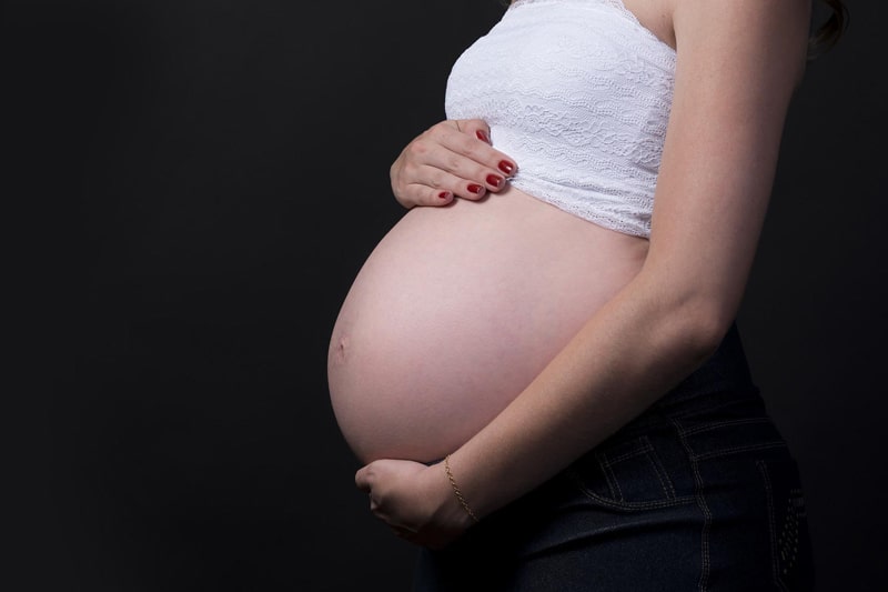 A pregnant women tenderly holds her stomach