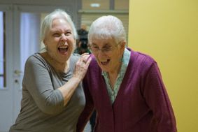 Two older women laughing as they exercise