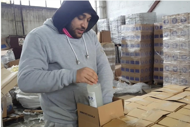 Tall man in hoodie works in factory, packing boxes