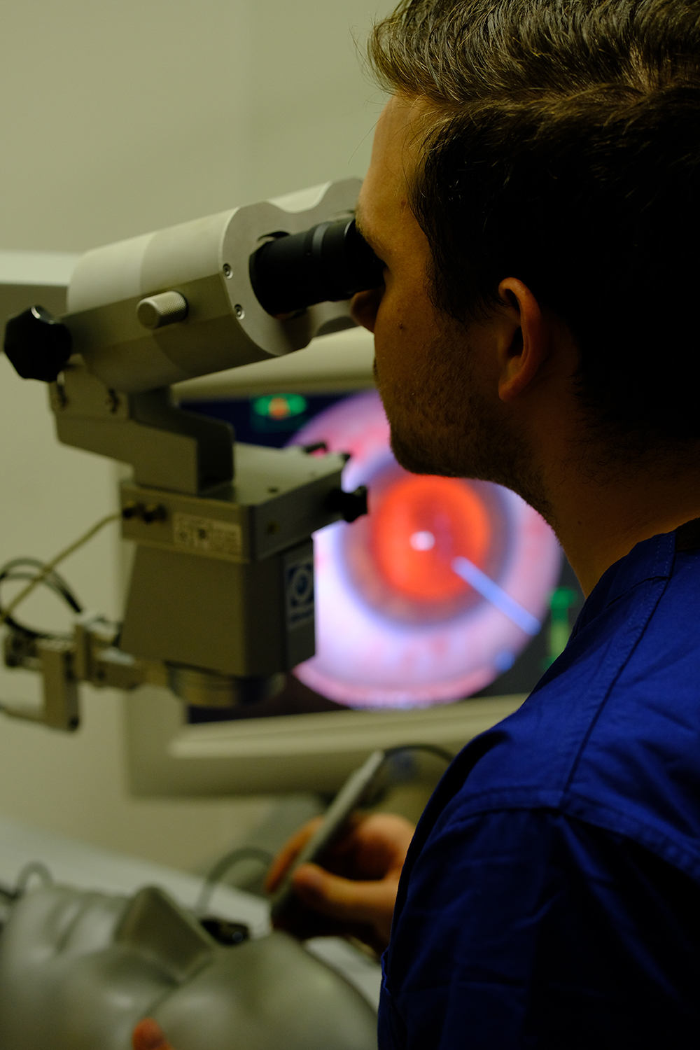 Rear view of a man looking into a microscope.