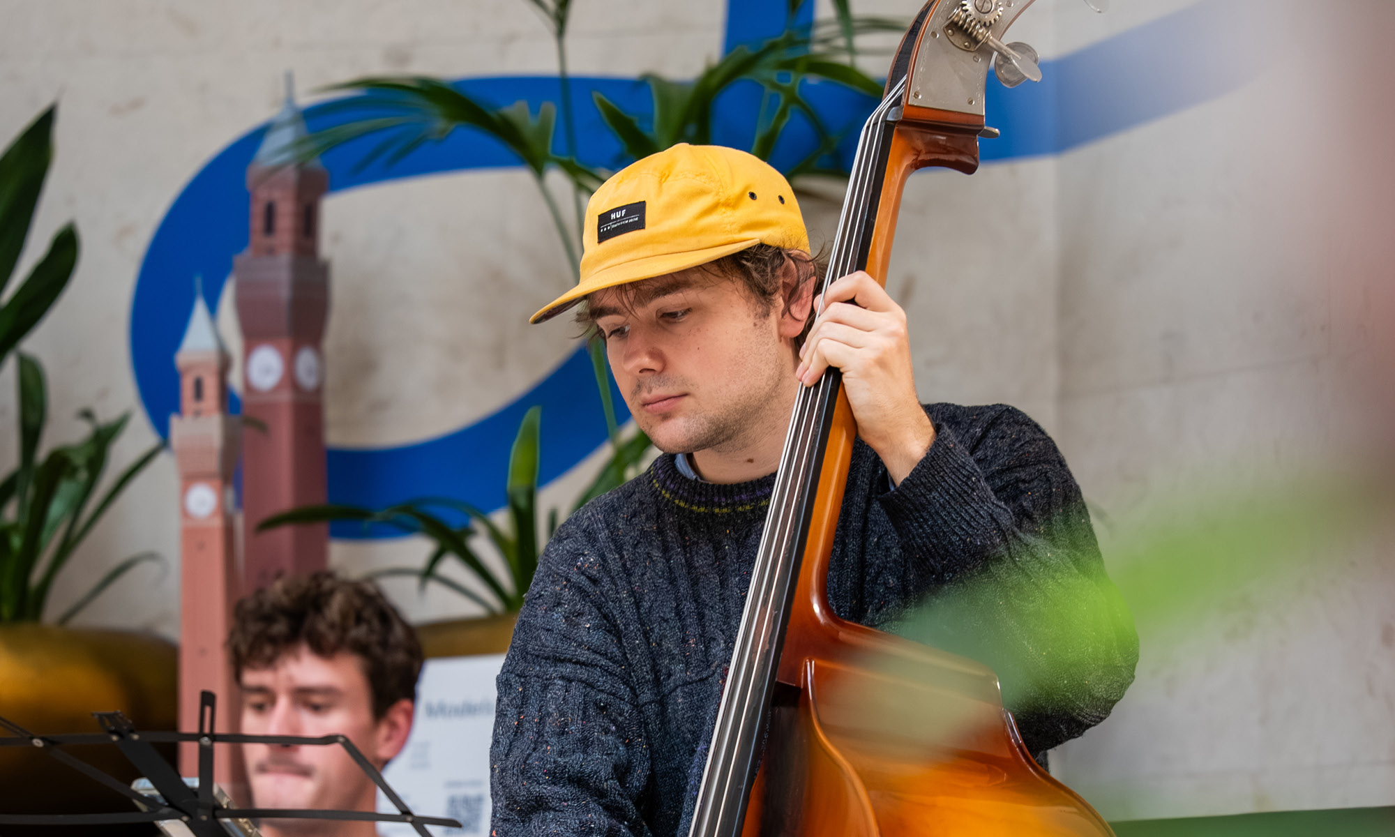 White male student in yellow cap playing an upright bass