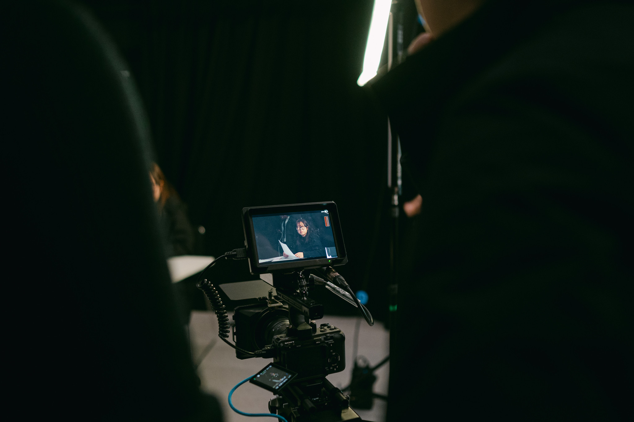 A dark studio with a film camera pointed at a student