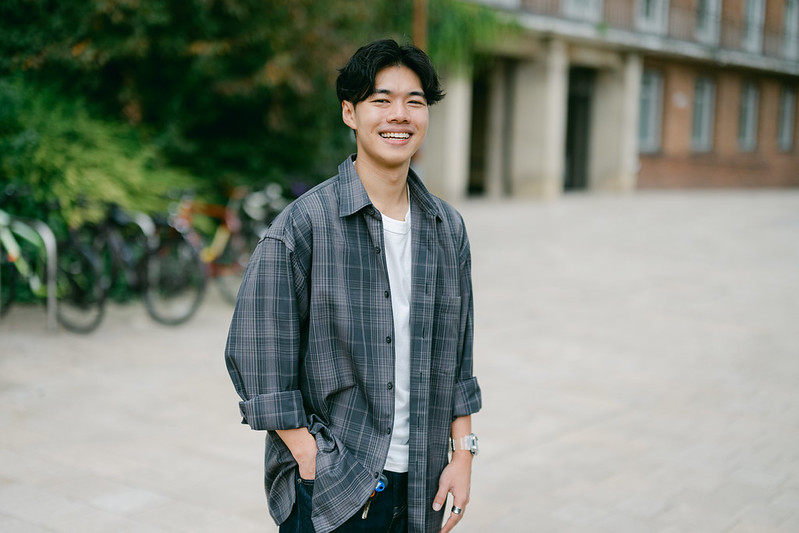 Portrait of student Matthew smiling in front of the arts building 
