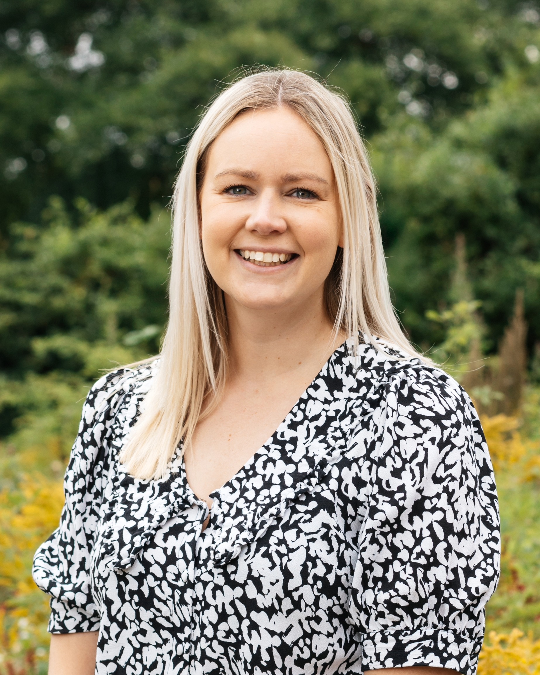 A portrait image of Jen wearing a black and white top with straight blonde hair