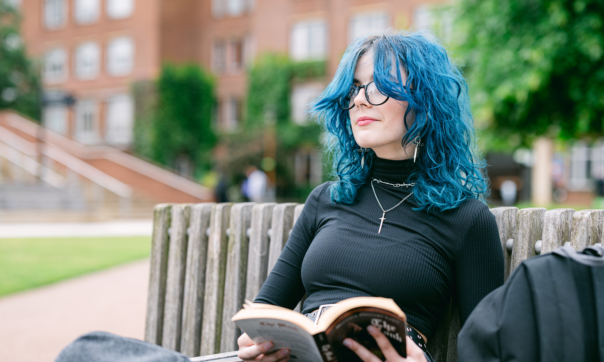 A student looking up from their book as they read outside on the University of Birmingham campus