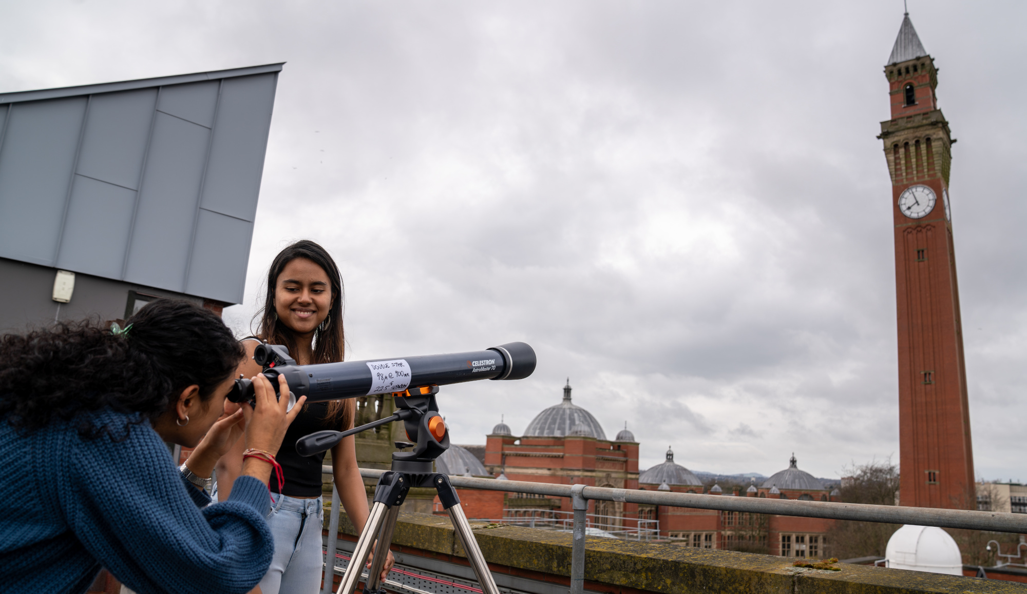 Two students on the roof with a telescope