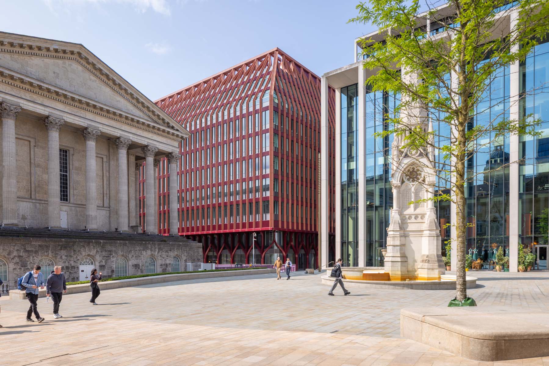 Greek/Italian style building with columns in front of modern red metal and glass building