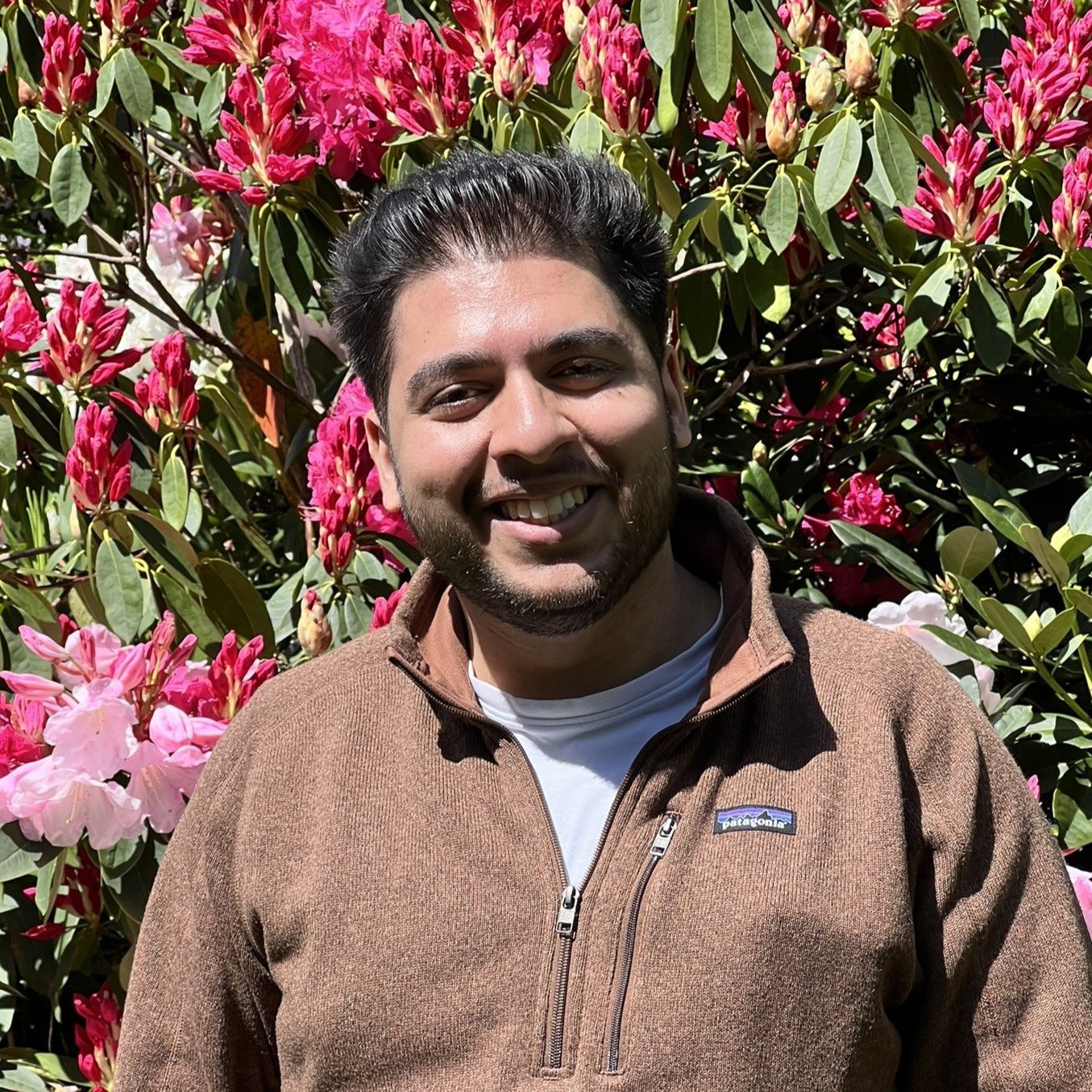 Jules standing in front of pink flowers.