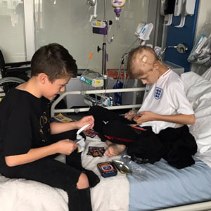 Twin boys playing card games on a hospital bed