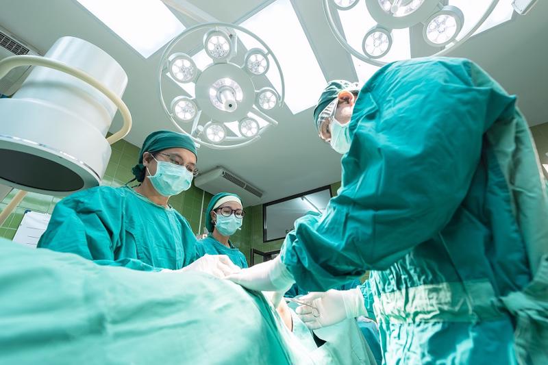 Three surgeons in PPE performing an operation in an operating theater