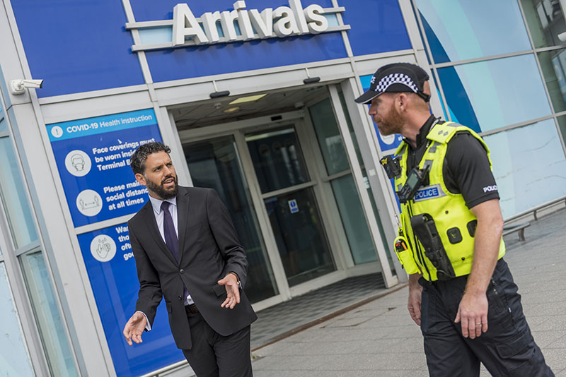Policeman talking to a man outside the arrivals lounge