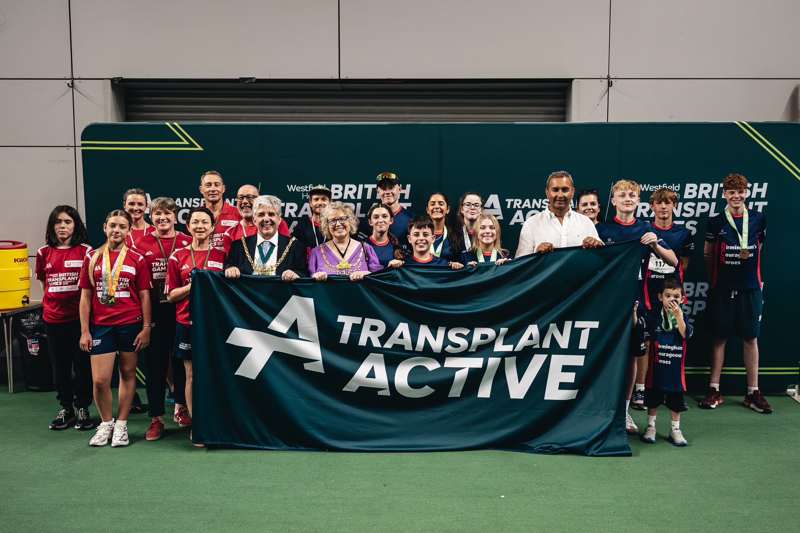 A group of people in sports kit hold a banner that reads Transplant Active