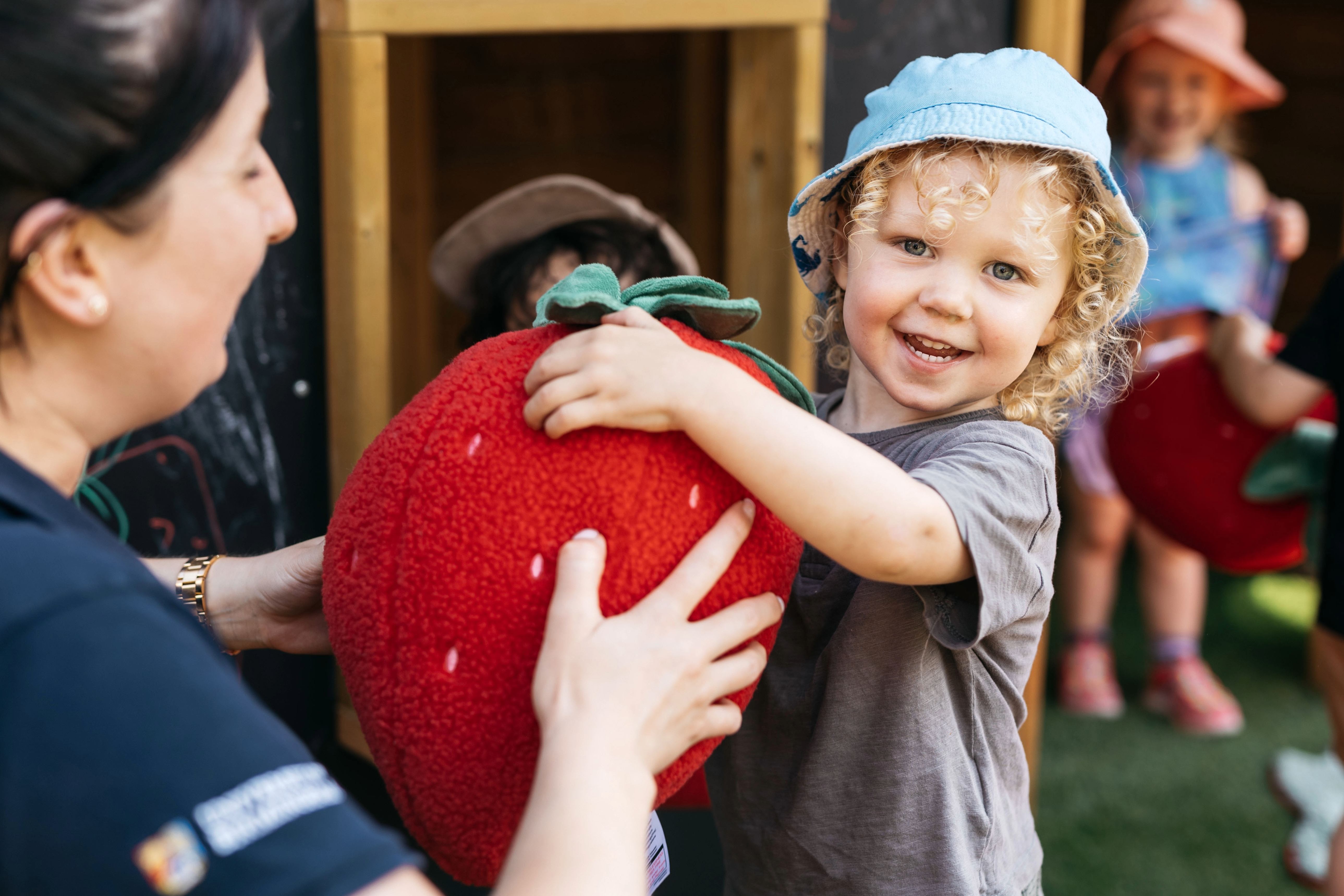 A child holding a large strawberry toy