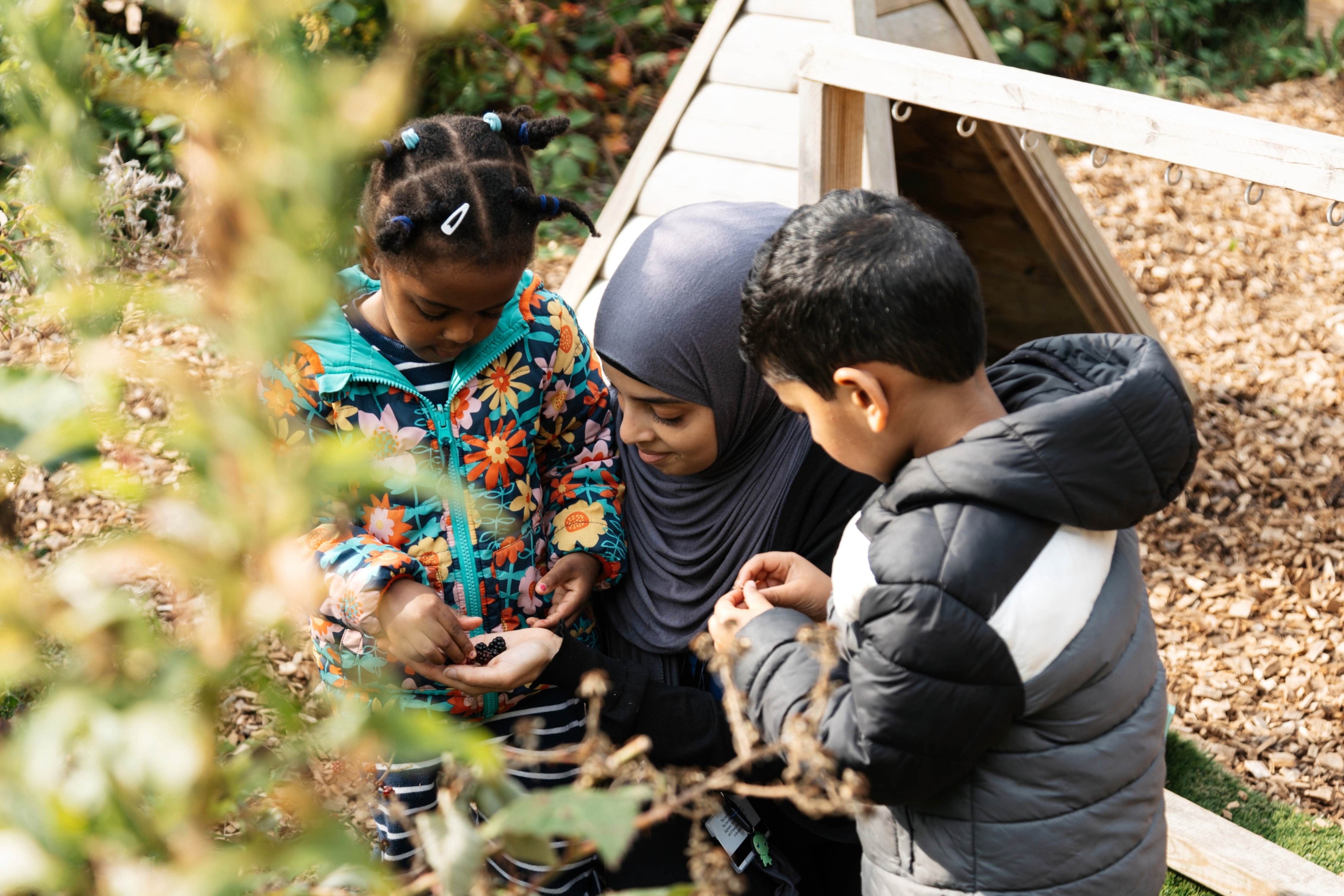 Children picking berries with a member of staff