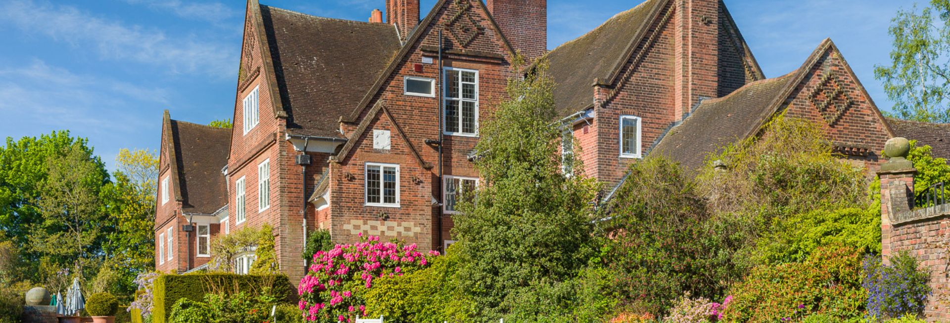 A large, old brick house surrounded by lush greenery